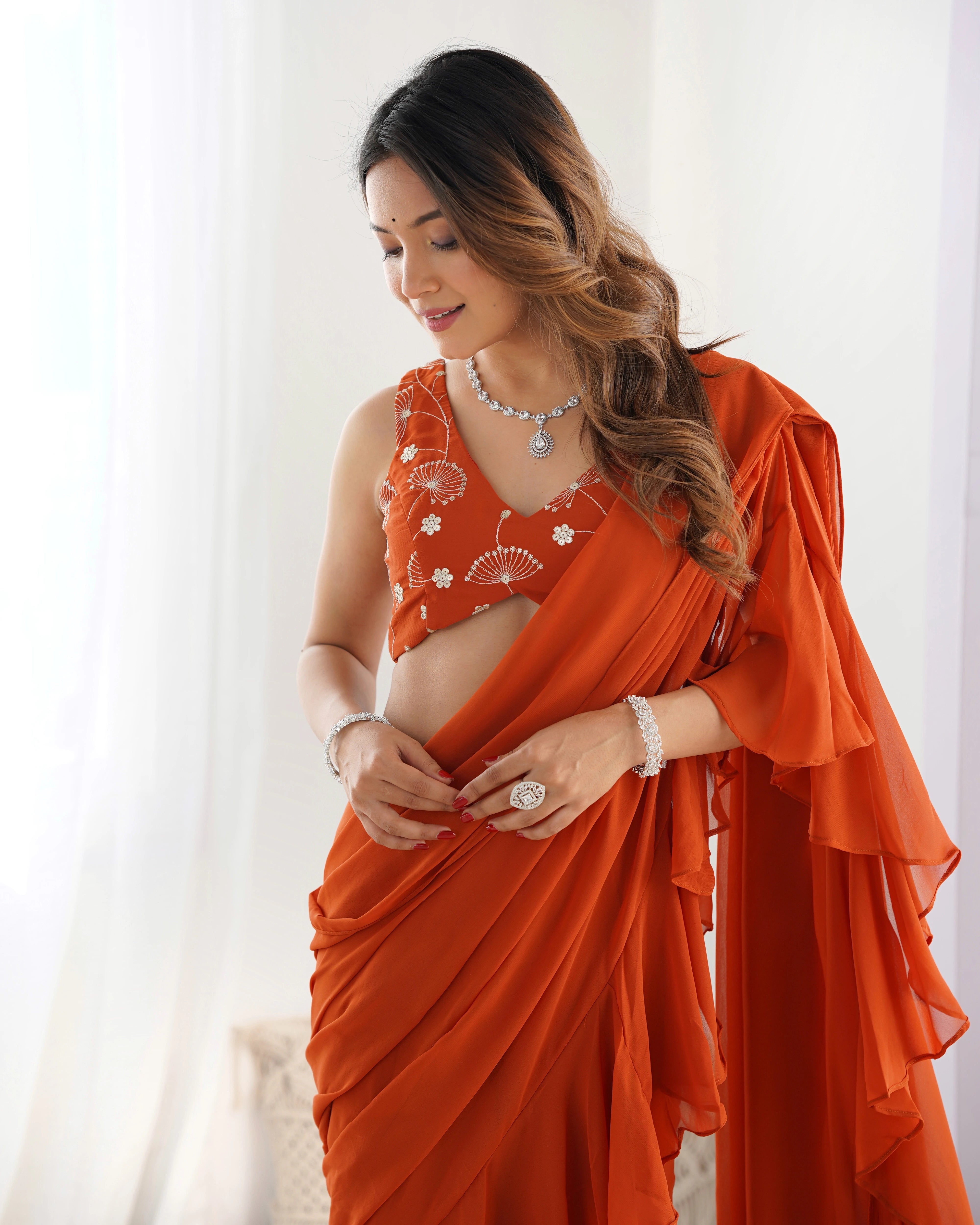 Woman wearing an orange saree with a white background